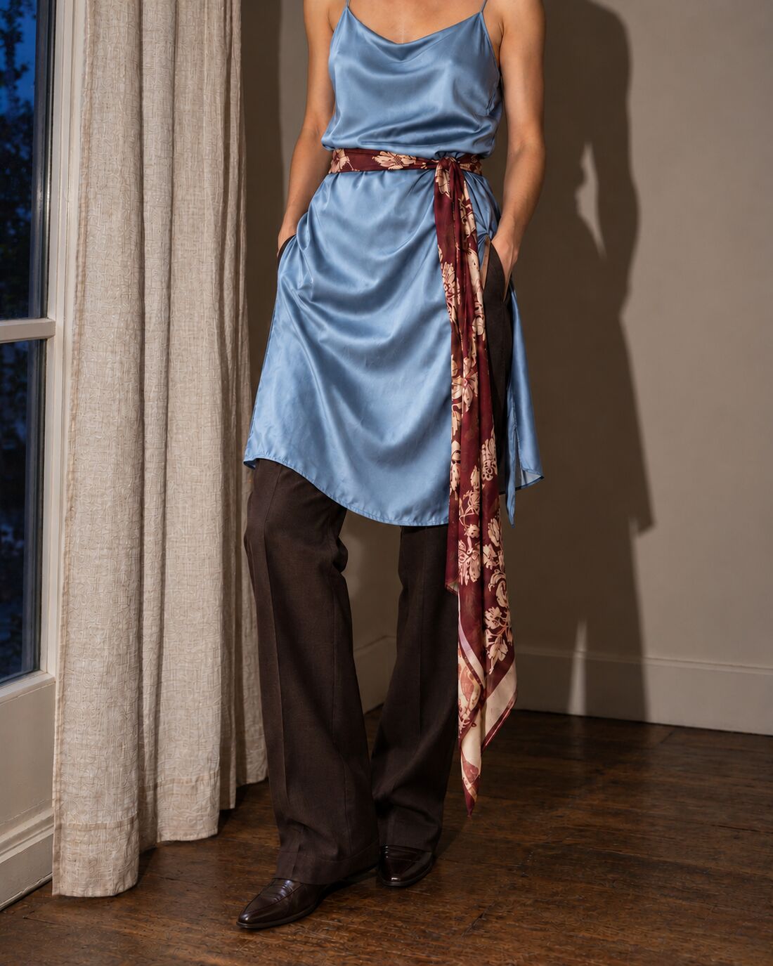 A slip dress worn over pants with a scarf as a belt